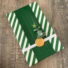 a green and white striped wrapping paper with a gold coin on the top, tied in ribbon