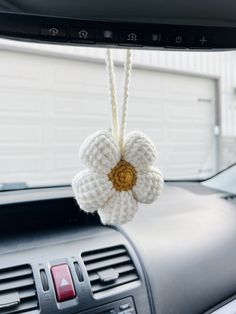 a crocheted flower hanging from the dash board of a car