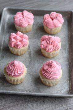 cupcakes with pink frosting on a baking sheet