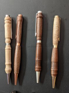 four different types of wooden pens lined up on a black wall next to each other