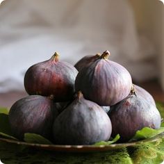 a bowl filled with figs sitting on top of a table