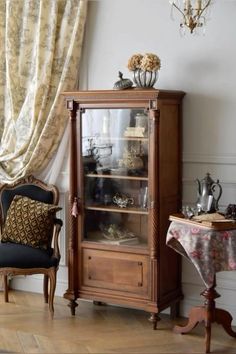 an antique china cabinet with glass doors and drawers in a living room next to a window