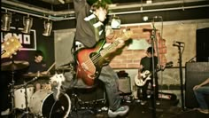 a group of young men playing guitars and singing into microphones in a music studio