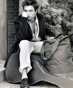 a man sitting on top of a guitar case