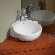 a white bowl sink sitting on top of a wooden counter