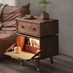 a wooden table with two drawers and a basket on it next to a brown couch