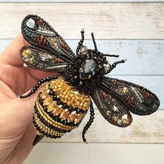 a hand holding a beaded insect on it's fingers