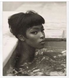 an old photo of a woman in the water with her hair up and eyes closed