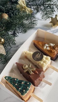 three pieces of cake sitting in a box next to a christmas tree