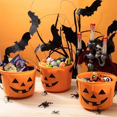 three halloween buckets filled with candy and decorations