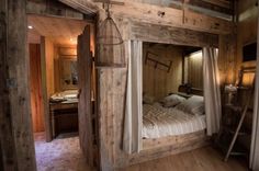 a bed in a room with wooden walls and flooring that is made out of wood planks