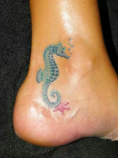 a foot with a blue and green seahorse tattoo on it's left side