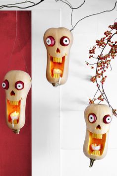 two halloween decorations hanging from the ceiling with eyes and mouths on them, one has a candle in its mouth