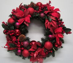 a red christmas wreath with poinsettis and berries