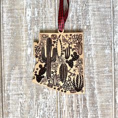 an ornament hanging on a wooden wall with cactus and succulents