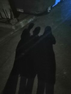 two people standing next to each other in the dark with their shadows on the ground