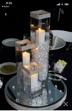 some candles are sitting in glass containers on a table