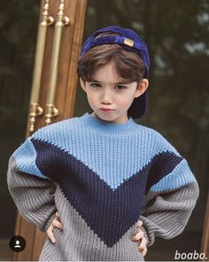 a young boy wearing a blue and gray sweater