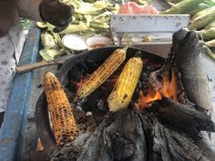 corn on the cob is being cooked over an open fire with other food items