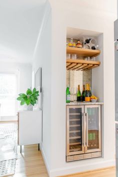 an open refrigerator in a kitchen next to a wall with shelves on it and bottles