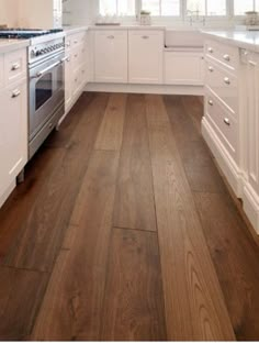 a kitchen with white cabinets and wood flooring on the walls is pictured in this image