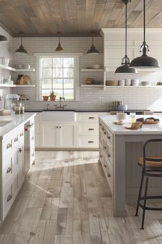 a kitchen with white cabinets and wood floors, an island countertop and two pendant lights