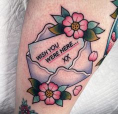 a woman's leg with flowers and a wish you were here sign on it