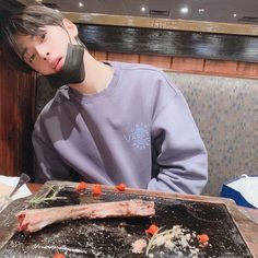 a person sitting at a table with food in front of him and covering his mouth