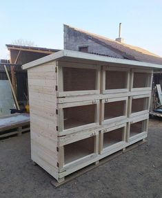 a building made out of wooden pallets in the middle of a dirt lot with a roof