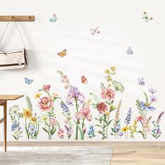 a wall with flowers and butterflies painted on it in a room next to a wooden table