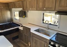 a kitchen area with sink, stove and cabinets in a trailer or camper home