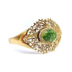 This is part of Chairish’s Fine Jewelry assortment.  This elegant bracelet is made of 14k gold and decorated with a central reticulated piece of green jade. The centre jade piece protrudes about a 1/4 of an inch from the gold setting and is carved with flower patterns. A lovely ring of seed pearls decorates the gold setting around the oval jade stone. From the central jade, as if emitting sinuous line-work, the gold work has a woven lace-like gold organic pattern detailed with beads of gold. The Elegant Green Cabochon Bracelets, Victorian Green Bracelets As Gift, Victorian Green Bracelet Jewelry, Victorian Green Bracelets For Gifts, Heirloom Jade Jewelry In Green, Green Cabochon Bracelet For Formal Occasions, Formal Yellow Gold Jade Bracelets, Victorian Style Green Bracelets For Gifts, Formal Yellow Gold Jade Bracelet