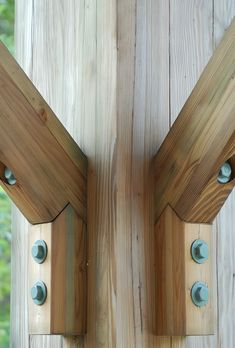 two wooden brackets are attached to the side of a wood structure with blue knobs