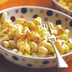 a bowl filled with macaroni and cheese on top of a table next to a fork