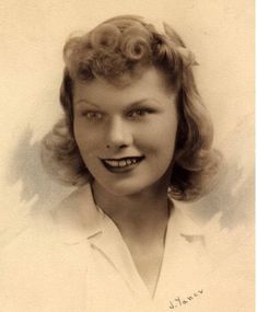 an old black and white photo of a woman with curly hair wearing a collared shirt