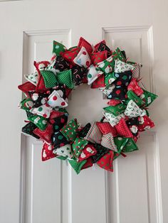 a christmas wreath on the front door with red, green and white bows hanging from it