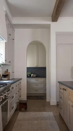 a kitchen with white cabinets and gray counter tops, along with a rug on the floor