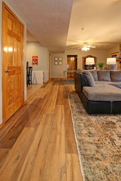 a living room filled with furniture on top of a hard wood floor covered in rugs