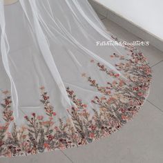 a wedding dress with flowers on it is laying on the floor in front of a wall