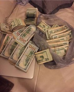 a pile of money sitting on top of a laptop computer