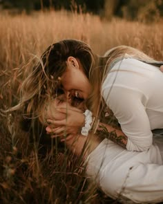 a woman kneeling down in the grass with her hands on her face and eyes closed