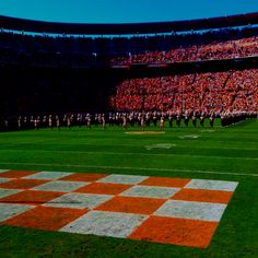 an orange and white checkered field in front of a large crowd at a football game