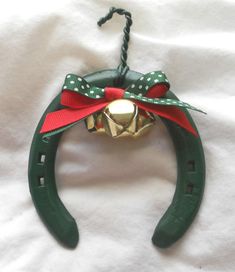 an ornament made out of green pliers with red ribbon and bells on them