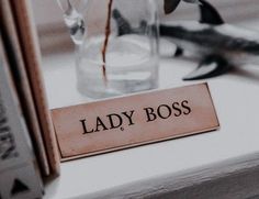 a lady boss sign sitting on top of a table next to a vase filled with flowers