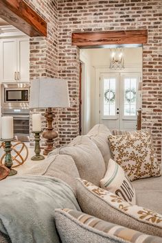 a living room filled with furniture next to a kitchen and dining room table in front of a brick wall