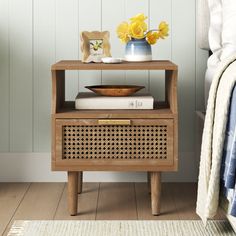 a wooden table with a basket on top and flowers in a vase sitting next to it