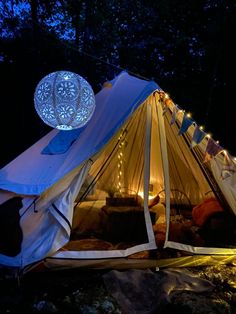 a tent is lit up at night with lights on the roof and curtains around it