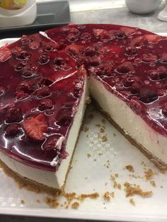 a cheesecake with berries on top is sitting on a white plate and has one slice cut out