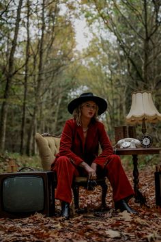 a woman in a red coat and hat sitting on a chair next to a tv