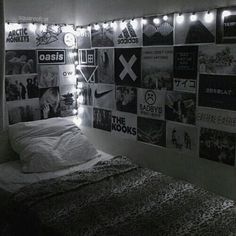 black and white photograph of a bedroom with posters on the wall above the bed,